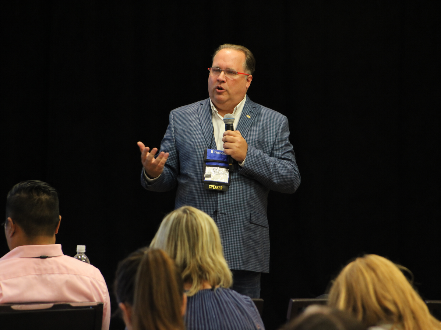 Kevin Knutson speaking with a handheld microphone before an audience at 3CMA in 2019